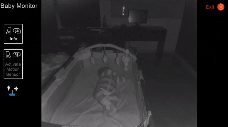 Night vision baby monitor view showing a sleeping baby in a crib with on screen motion sensor controls