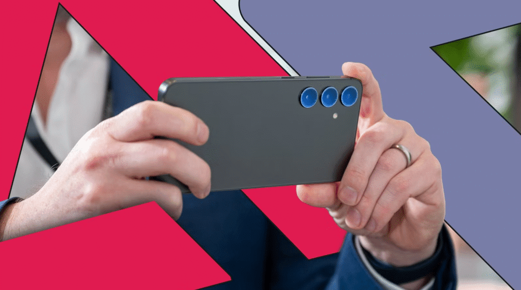 Hands holding a smartphone in landscape mode with triple rear cameras against a colorful geometric background